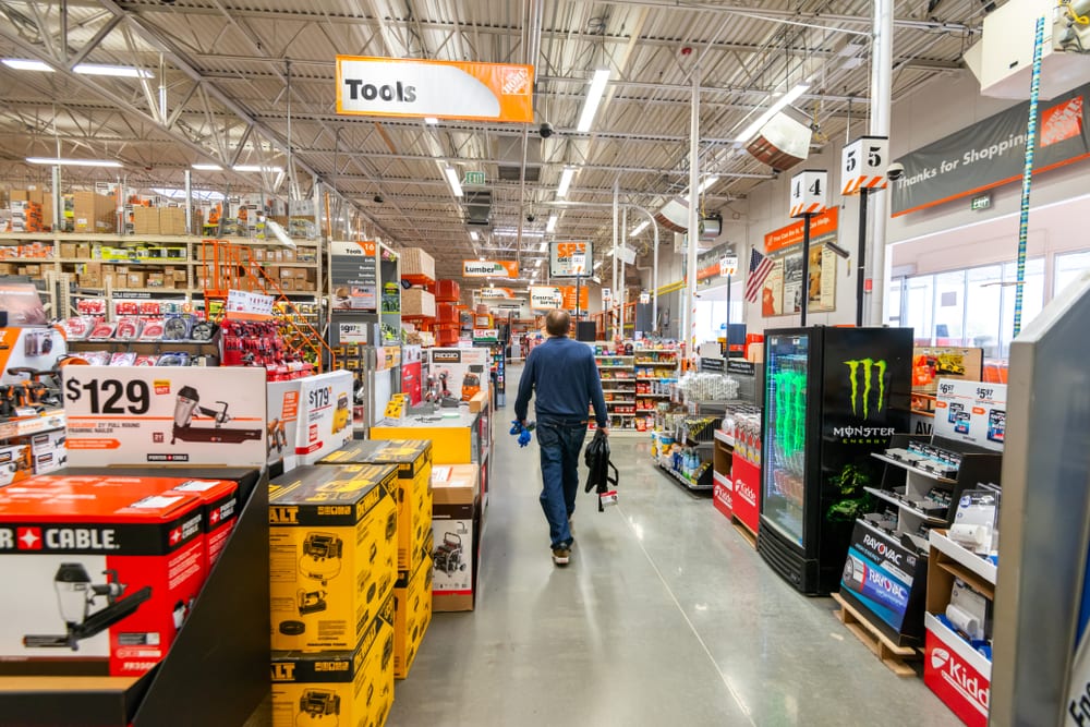 man walking through Home Depot, painted metal deck is visible on the ceiling.