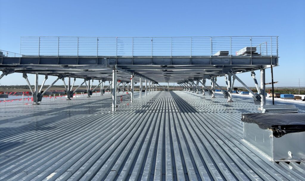 Galvanized roof deck installed across a large data center structure with steel framing and rooftop platform supports.