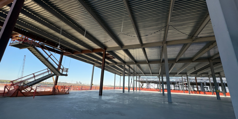 Interior view of a data center under construction with steel framing, metal deck overhead, and a finished concrete floor.
